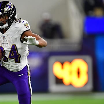 Nov 26, 2023; Inglewood, California, USA; Baltimore Ravens running back Keaton Mitchell (34) runs the ball ahead of Los Angeles Chargers cornerback Asante Samuel Jr. (26) during the first half at SoFi Stadium. Mandatory Credit: Gary A. Vasquez-Imagn Images