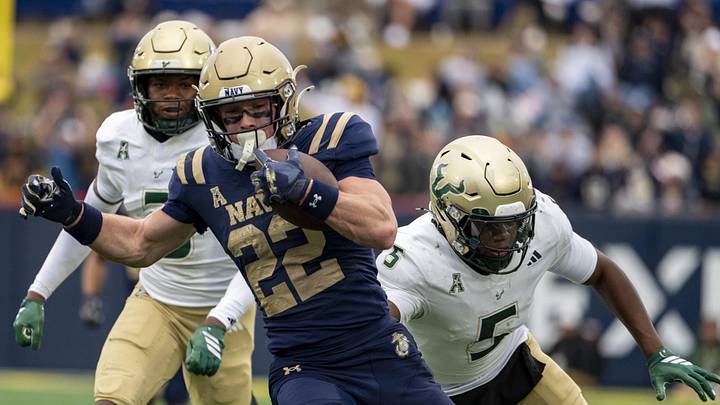 Navy running back Eli Heidenreich (22) runs by South Florida defensive back Fred Gaskin (5)  for some of the Midshipmen's 338 rushing yards.