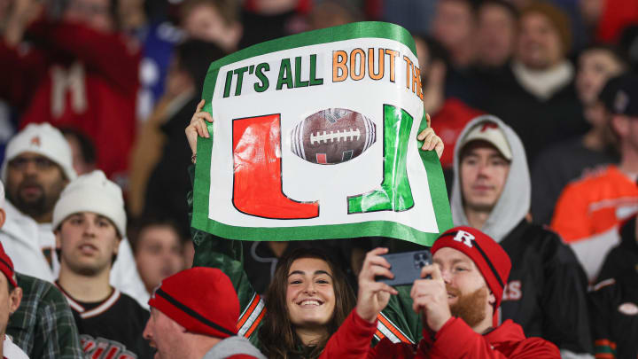 Dec 28, 2023; Bronx, NY, USA; A Miami Hurricanes fan holds a sign during the second half of the 2023 Pinstripe Bowl in front of Rutgers Scarlet Knights fans at Yankee Stadium. Mandatory Credit: Vincent Carchietta-USA TODAY Sports