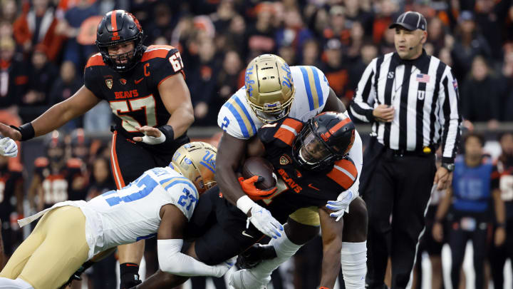 Oct 14, 2023; Corvallis, Oregon, USA; Oregon State Beavers running back Deshaun Fenwick (1) is tackled by UCLA Bruins defensive back Kamari Ramsey (27) and linebacker Oluwafemi Oladejo (2) during the first half at Reser Stadium. Mandatory Credit: Soobum Im-USA TODAY Sports