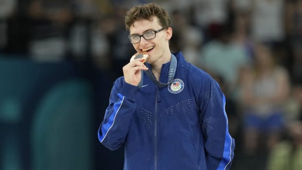 Team USA gymnast Stephen Nedoroscik bites his bronze medal as he poses for a photo at the Paris Olympics.