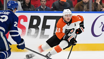 Mar 25, 2025; Toronto, Ontario, CAN;  Philadelphia Flyers forward Travis Konecny (11) moves the puck away from Toronto Maple Leafs defenseman Jake McCabe (22) in the second period at Scotiabank Arena. Mandatory Credit: Dan Hamilton-Imagn Images
