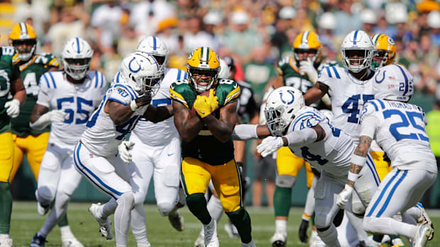 Green Bay Packers running back Josh Jacobs runs for a first down in a green jersey.