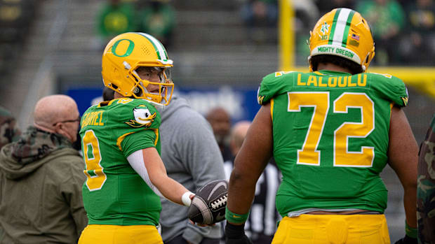 Oregon quarterback Dillon Gabriel passes the ball off to Oregon offensive lineman Iapani Laloulu during warmups