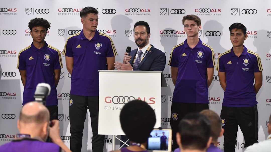 Jul 31, 2019; Orlando, FL, USA; Orlando City SC executive vice president of soccer operations Luiz Muzzi (at podium) speaks during a press conference as development players from Orlando City look on before the 2019 MLS All Star Game at Exploria Stadium. Mandatory Credit: Jasen Vinlove-Imagn Images