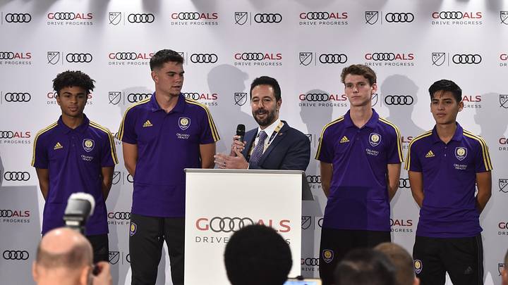 Jul 31, 2019; Orlando, FL, USA; Orlando City SC executive vice president of soccer operations Luiz Muzzi (at podium) speaks during a press conference as development players from Orlando City look on before the 2019 MLS All Star Game at Exploria Stadium. Mandatory Credit: Jasen Vinlove-Imagn Images