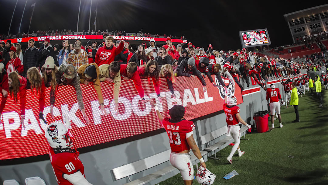 Nov 29, 2025; Raleigh, North Carolina, USA;  NC State Wolfpack fans celebrate with the team after the second half of the game against North Carolina Tar Heels at Carter-Finley Stadium.  Mandatory Credit: Jaylynn Nash-Imagn Images