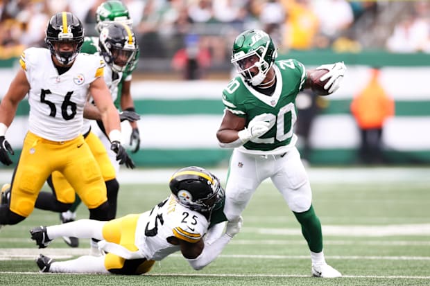 Football player in white uniform attempts tackle on player in green uniform