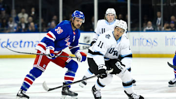 Oct 12, 2024; New York, New York, USA; Utah Hockey Club right wing Dylan Guenther (11) skates with the puck against New York Rangers center Sam Carrick (39) during the first period at Madison Square Garden. Mandatory Credit: John Jones-Imagn Images