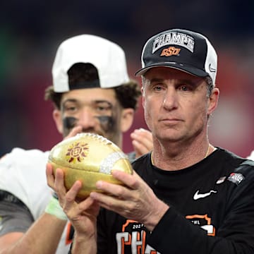 Jan 1, 2022; Glendale, Arizona, USA; Oklahoma State Cowboys head coach Mike Gundy celebrates with the trophy after defeating the Notre Dame Fighting Irish in the 2022 Fiesta Bowl at State Farm Stadium. Mandatory Credit: Joe Camporeale-Imagn Images