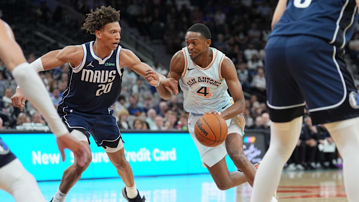 Mar 12, 2025; San Antonio, Texas, USA; San Antonio Spurs guard De'Aaron Fox (4) dribbles against Dallas Mavericks forward Kessler Edwards (20) in the first half at Frost Bank Center. Mandatory Credit: Daniel Dunn-Imagn Images