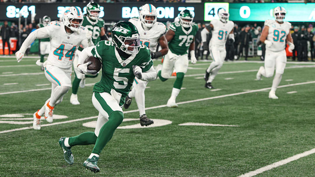 Jan 5, 2025; East Rutherford, New Jersey, USA; New York Jets wide receiver Garrett Wilson (5) gains yards after catch as Miami Dolphins linebacker Chop Robinson (44) pursues during the first half at MetLife Stadium. Mandatory Credit: Vincent Carchietta-Imagn Images