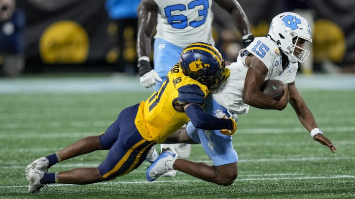 Dec 27, 2023; Charlotte, NC, USA; West Virginia Mountaineers cornerback Beanie Bishop Jr. (11) tackles North Carolina Tar Heels quarterback Conner Harrell (15) during the first half at Bank of America Stadium.