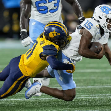 Dec 27, 2023; Charlotte, NC, USA; West Virginia Mountaineers cornerback Beanie Bishop Jr. (11) tackles North Carolina Tar Heels quarterback Conner Harrell (15) during the first half at Bank of America Stadium. Mandatory Credit: Jim Dedmon-USA TODAY Sports