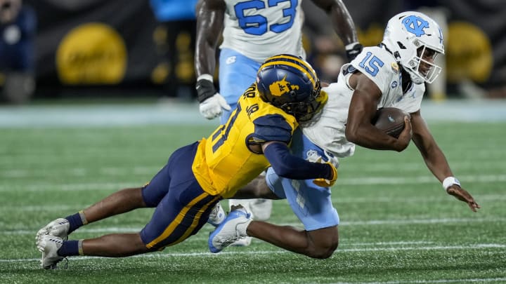 Dec 27, 2023; Charlotte, NC, USA; West Virginia Mountaineers cornerback Beanie Bishop Jr. (11) tackles North Carolina Tar Heels quarterback Conner Harrell (15) during the first half at Bank of America Stadium. Mandatory Credit: Jim Dedmon-USA TODAY Sports