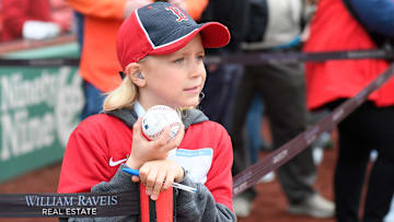 A young Boston Red Sox fan waits for players to walk by in hopes of getting a ball autographed before a game against the San Francisco Giants at Fenway Park.