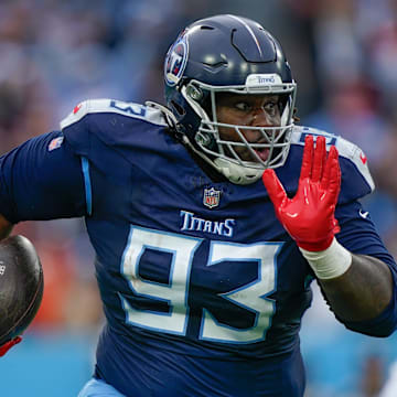 Tennessee Titans defensive tackle T'Vondre Sweat returns the ball after stripping it from Cincinnati Bengals quarterback Joe Burrow.