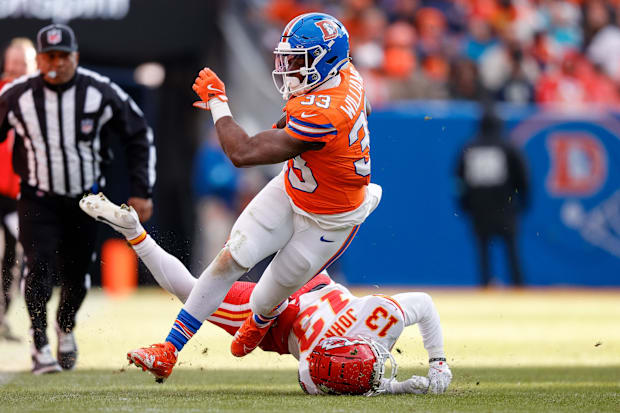Denver Broncos running back Javonte Williams  runs through the tackle of Kansas City Chiefs cornerback Nic Jones