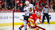 Nov 7, 2025; Calgary, Alberta, CAN; Calgary Flames defenseman Zayne Parekh (19) and Chicago Blackhawks center Connor Bedard (98) battles for the puck as Calgary Flames goaltender Dustin Wolf (32) makes a save during the first period at Scotiabank Saddledome. Mandatory Credit: Sergei Belski-Imagn Images