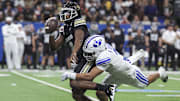 Colorado Buffaloes quarterback Shedeur Sanders is tackled by Brigham Young Cougars safety Raider Damuni during the Alamo Bowl.