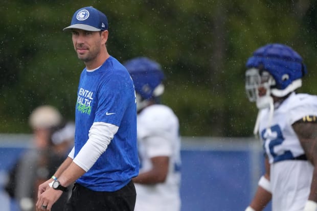 Football coach Shane Steichen watches practice in a blue shirt.