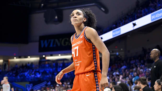 A female basketball player in an orange uniform that says