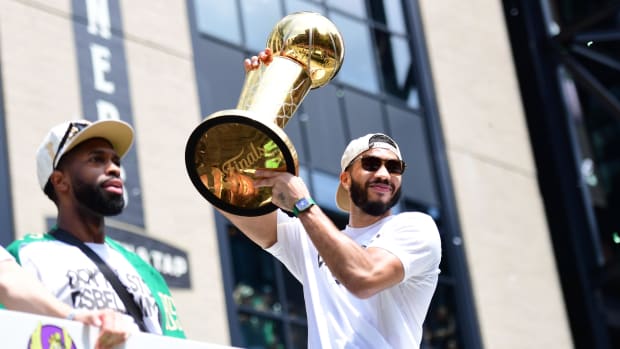 Celtics star Jayson Tatum hoists the Larry O'Brien Trophy while on a duck boat during the team's 2024 championship parade.