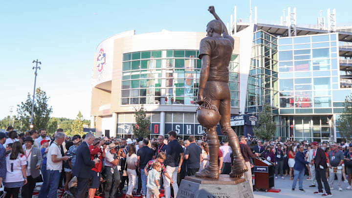 Retired New England Patriot Hall of Famer Tom Brady reacts during a NFL statue unveiling against the Washington Commanders Retired New England Patriot Hall of Famer Tom Brady reacts during a NFL statue unveiling against the Washington Commanders