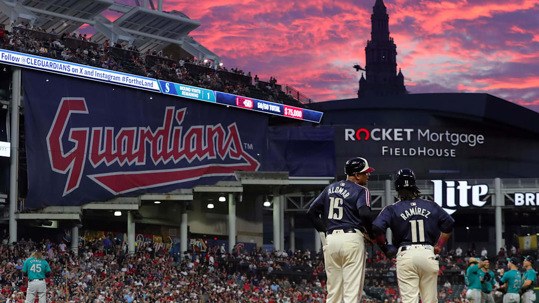 Cleveland Guardians first base coach Sandy Alomar Jr. (15) chats with Jose Ramirez as the sun sets during a game against the Seattle Mariners on June 18, 2024, in Cleveland, Ohio.