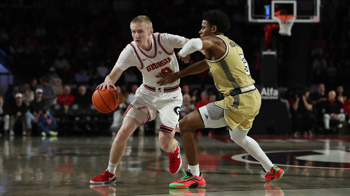 Nov 14, 2025; Athens, Georgia, USA;  Georgia Bulldogs guard Blue Cain (0) dribbles against Georgia Tech Yellow Jackets guard Jaeden Mustaf (3) during the first half at Stegeman Coliseum. Mandatory Credit: Mady Mertens-Imagn Images