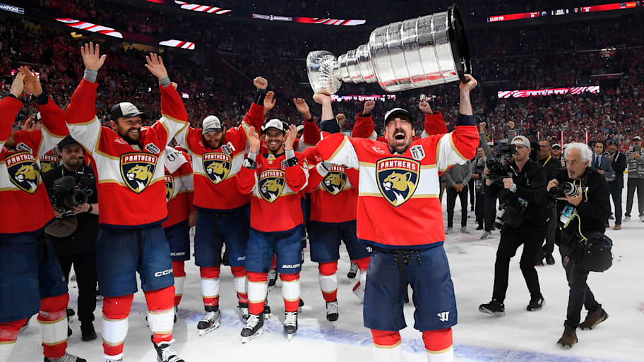 Brad Marchand holds the Stanley Cup trophy while his Florida Panthers teammates celebrate.  | Brian Babineau/NHLI via Getty Images
