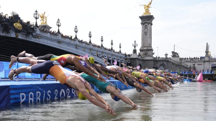 Athletes dive into the Seine River at the start of the men's triathlon during the Paris Games.