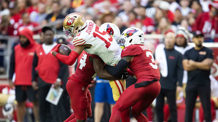 Jan 5, 2025; Glendale, Arizona, USA; San Francisco 49ers wide receiver Jauan Jennings (15) is tackled by Arizona Cardinals safety Budda Baker (3) and cornerback Starling Thomas V (24) in the first half at State Farm Stadium. Mandatory Credit: Mark J. Rebilas-Imagn Images Jan 5, 2025; Glendale, Arizona, USA; San Francisco 49ers wide receiver Jauan Jennings (15) is tackled by Arizona Cardinals safety Budda Baker (3) and cornerback Starling Thomas V (24) in the first half at State Farm Stadium. Mandatory Credit: Mark J. Rebilas-Imagn Images