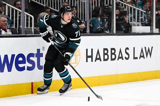 Hockey player in black uniform skates with the puck