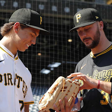 Jul 22, 2025; Pittsburgh, Pennsylvania, USA;  Seth Hernandez (left) the Pittsburgh Pirates first round and number six overall pick in the 2025 first year player draft looks at the glove of Pirates pitcher Paul Skenes (30) before the game against the Detroit Tigers at PNC Park. Mandatory Credit: Charles LeClaire-Imagn Images