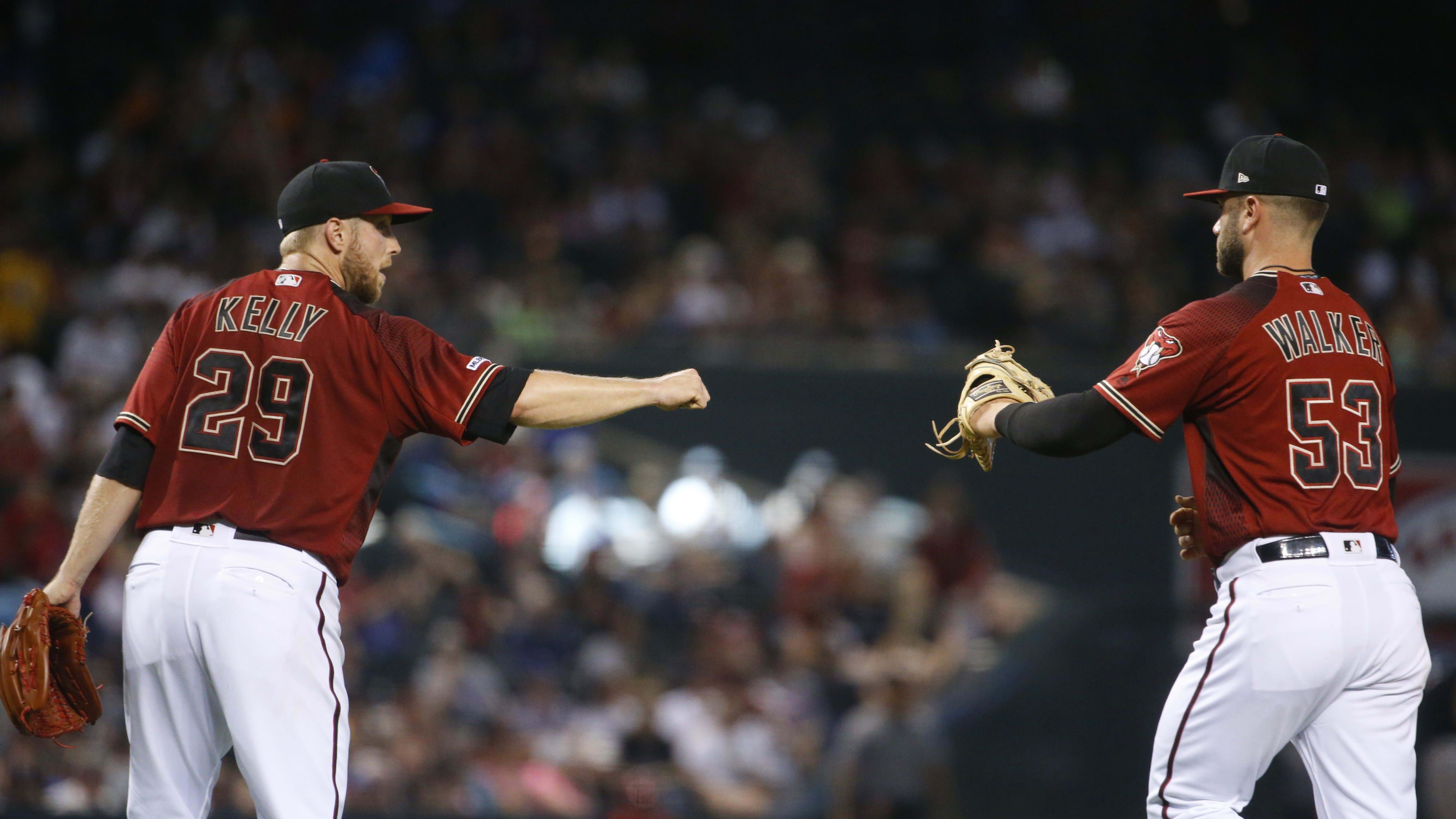 Diamondbacks' Merrill Kelly (29) bumps fists with first basemen Christian Walker (53) 