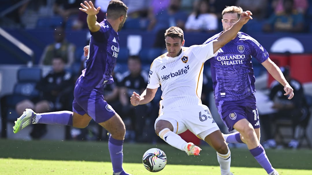 Aug 31, 2025; Carson, California, USA; LA Galaxy midfielder Chris Rindov (63) passes the ball in front of Orlando City SC forward Duncan McGuire (13)  during the second half at Dignity Health Sports Park. Mandatory Credit: Kelvin Kuo-Imagn Images