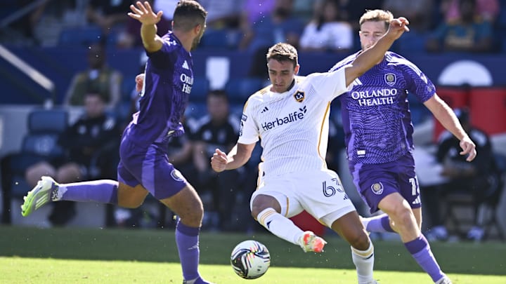 Aug 31, 2025; Carson, California, USA; LA Galaxy midfielder Chris Rindov (63) passes the ball in front of Orlando City SC forward Duncan McGuire (13)  during the second half at Dignity Health Sports Park. Mandatory Credit: Kelvin Kuo-Imagn Images