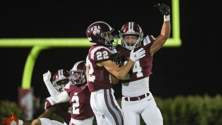 First Baptist Academy Lions corner back Logan Bartley (24) and running back Sam Sparacio (22) celebrate after a turnover during the first quarter of the Class 1S state semifinal against the Munroe Bobcats at First Baptist Academy in Naples on Friday, Dec. 2, 2022.