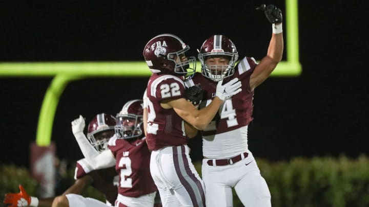 First Baptist Academy Lions corner back Logan Bartley (24) and running back Sam Sparacio (22) celebrate after a turnover during the first quarter of the Class 1S state semifinal against the Munroe Bobcats at First Baptist Academy in Naples on Friday, Dec. 2, 2022.