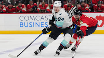 Feb 22, 2025; Sunrise, Florida, USA;  Seattle Kraken right wing Kaapo Kakko (84) controls the puck as Florida Panthers defenseman Aaron Ekblad (5) closes in during the first period at Amerant Bank Arena. Mandatory Credit: Jim Rassol-Imagn Images