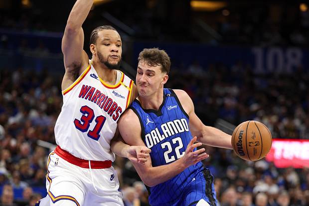 Tiền đạo Franz Wagner của Orlando Magic lái bóng vào rổ vượt qua tiền đạo Kevin Knox II của Golden State Warriors.