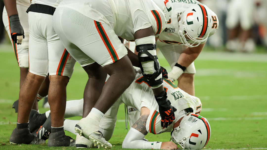 Jan 19, 2026; Miami Gardens, FL, USA; Miami Hurricanes quarterback Carson Beck (11) is checked on by teammates after a play against the Indiana Hoosiers in the fourth quarter during the College Football Playoff National Championship game at Hard Rock Stadium. 