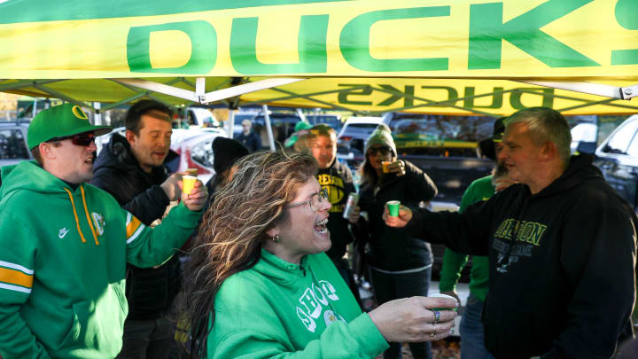 Denyse Renner, center, takes shots with other Oregon fans as they tailgate before the annual rivalry game on Friday, Nov. 24, 2023 at Autzen Stadium in Eugene, Ore.