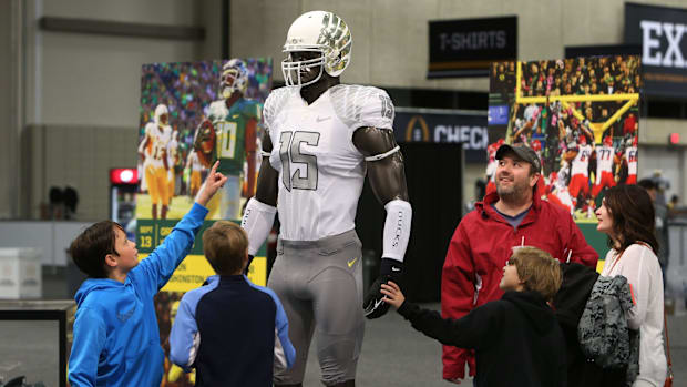 Football fans gather around mannequin wearing a version of the Oregon white and silver uniform at Fan Center in Dallas, Texas