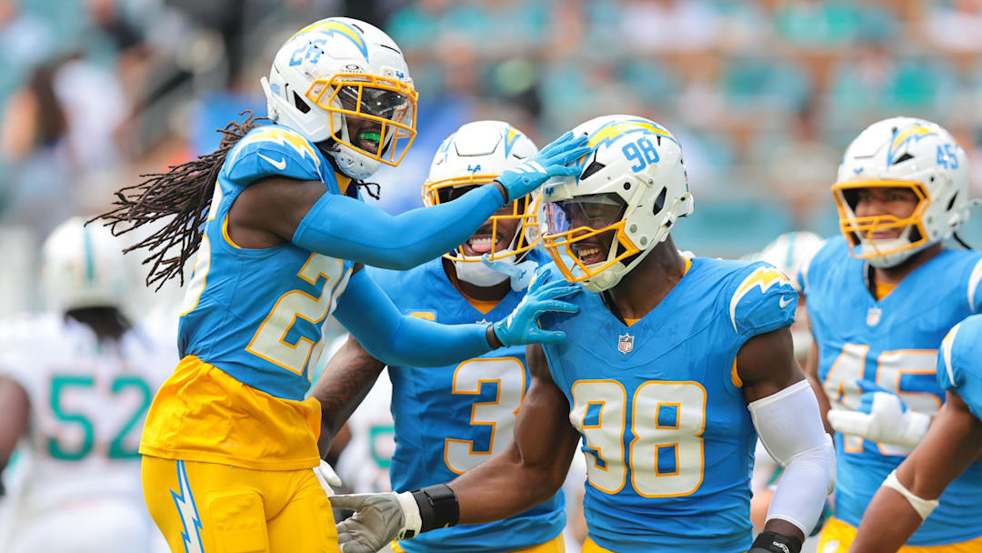 Oct 12, 2025; Miami Gardens, Florida, USA; Los Angeles Chargers offensive linebacker Odafe Oweh (98) celebrates with cornerback Donte Jackson (26) after a sacking Miami Dolphins quarterback Tua Tagovailoa (not pictured) during the first quarter at Hard Rock Stadium. 