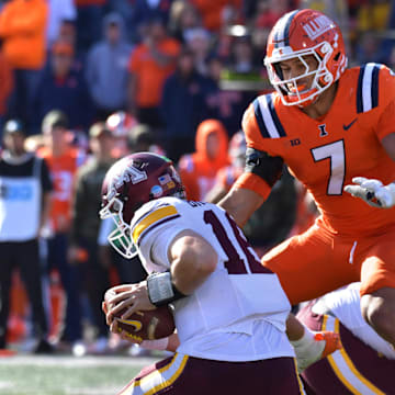 Nov 2, 2024; Champaign, Illinois, USA;  Illinois Fighting Illini defensive back Matthew Bailey (7) leaps over Minnesota Golden Gophers offensive lineman Phillip Daniels (60) to get to Minnesota Golden Gophers quarterback Max Brosmer (16) during the second half at Memorial Stadium. Mandatory Credit: Ron Johnson-Imagn Images