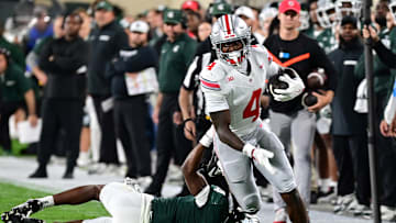 Sep 28, 2024; East Lansing, Michigan, USA;  Ohio State Buckeyes wide receiver Jeremiah Smith (4) runs past Michigan State Spartans defensive back Ed Woods (4) in the first quarter at Spartan Stadium. Mandatory Credit: Dale Young-Imagn Images
