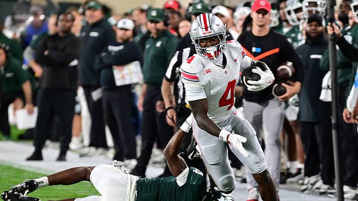 Sep 28, 2024; East Lansing, Michigan, USA;  Ohio State Buckeyes wide receiver Jeremiah Smith (4) runs past Michigan State Spartans defensive back Ed Woods (4) in the first quarter at Spartan Stadium. Mandatory Credit: Dale Young-Imagn Images
