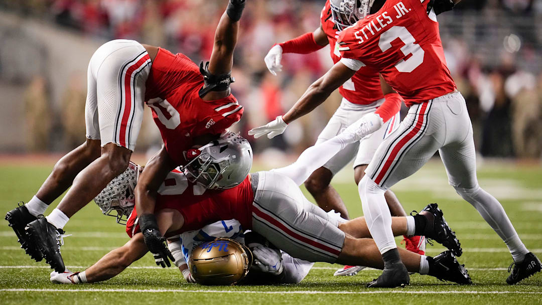 Ohio State Buckeyes defensive end Caden Curry (92), linebacker Sonny Styles (0), and cornerback Lorenzo Styles Jr. (3) tackle UCLA Bruins wide receiver Mikey Matthews (7).